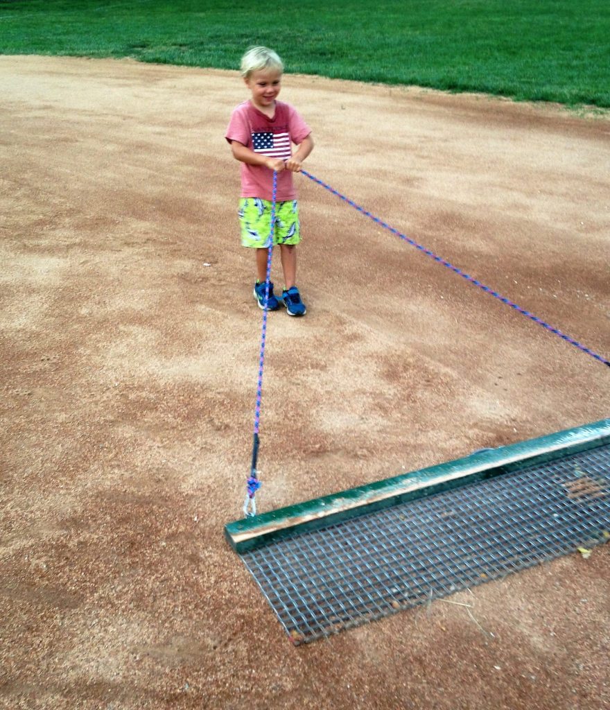 little kid pulling the tarp on field 