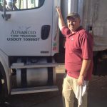 employee smiling in front of truck