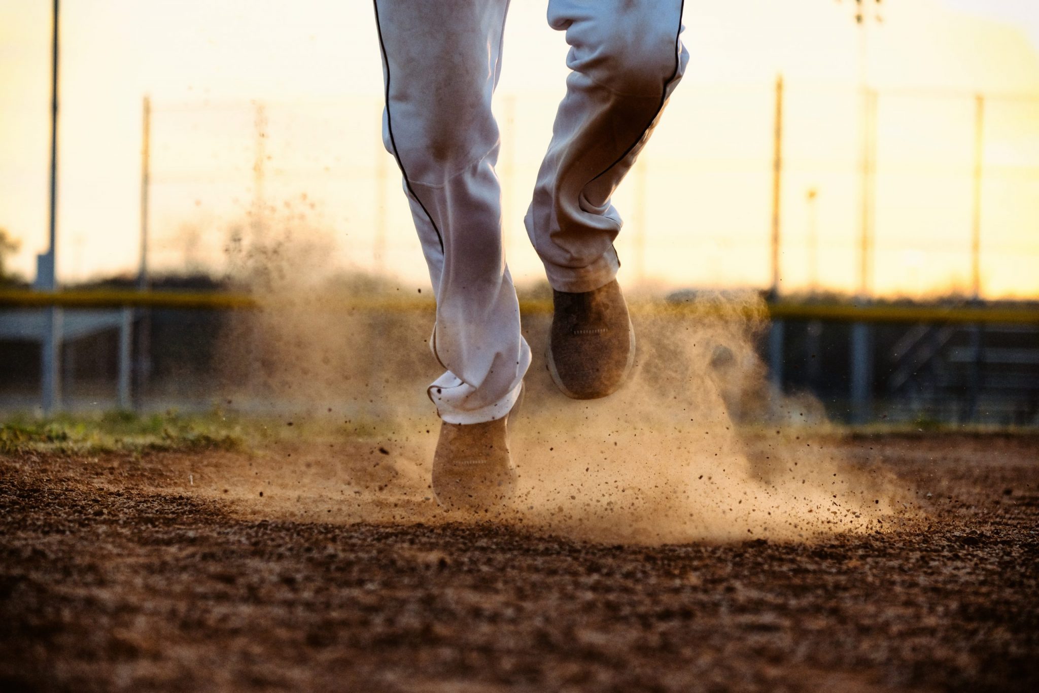 Baseball player feet running to base on field, dirt and dust moving from action of athlete