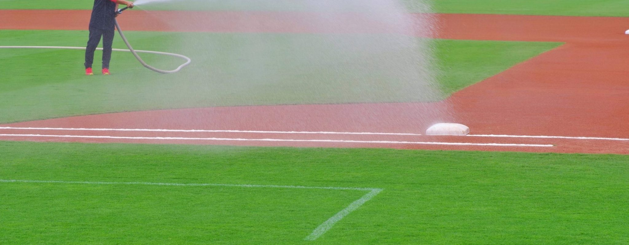 Person using hose to water infield of baseball field
